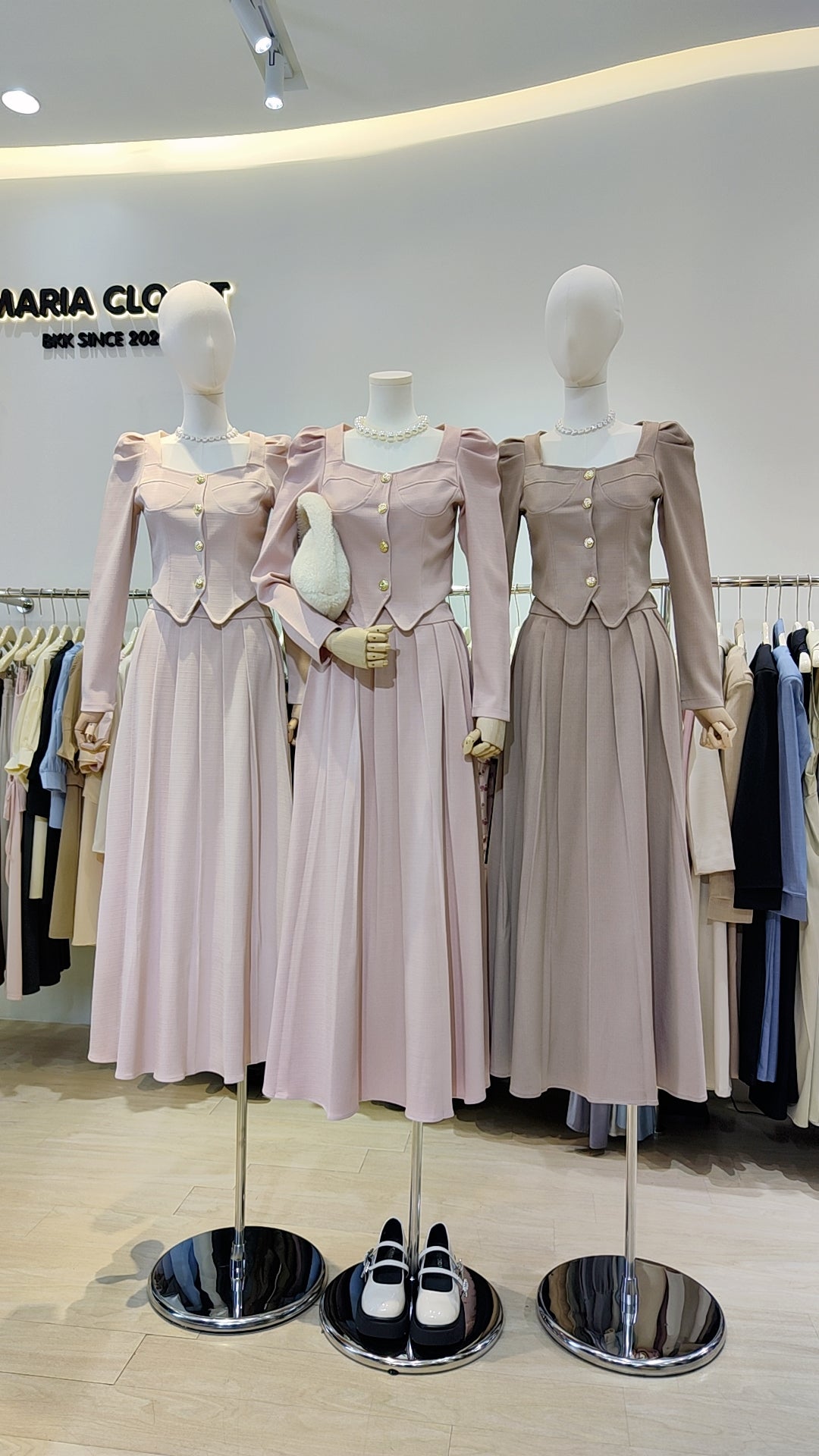 Three mannequins wearing The "Flowy Tweed" Co-ord Set featuring long skirts and buttoned tops in soft pastel colors.