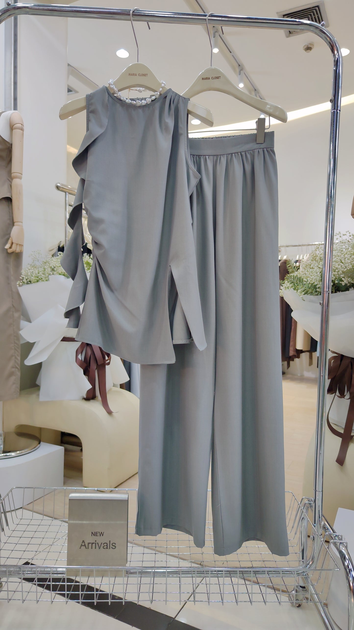 The "Flowy Tunic" Two-Piece Set in soft gray with sleeveless ruffle hem top and wide-leg trousers on hanger.