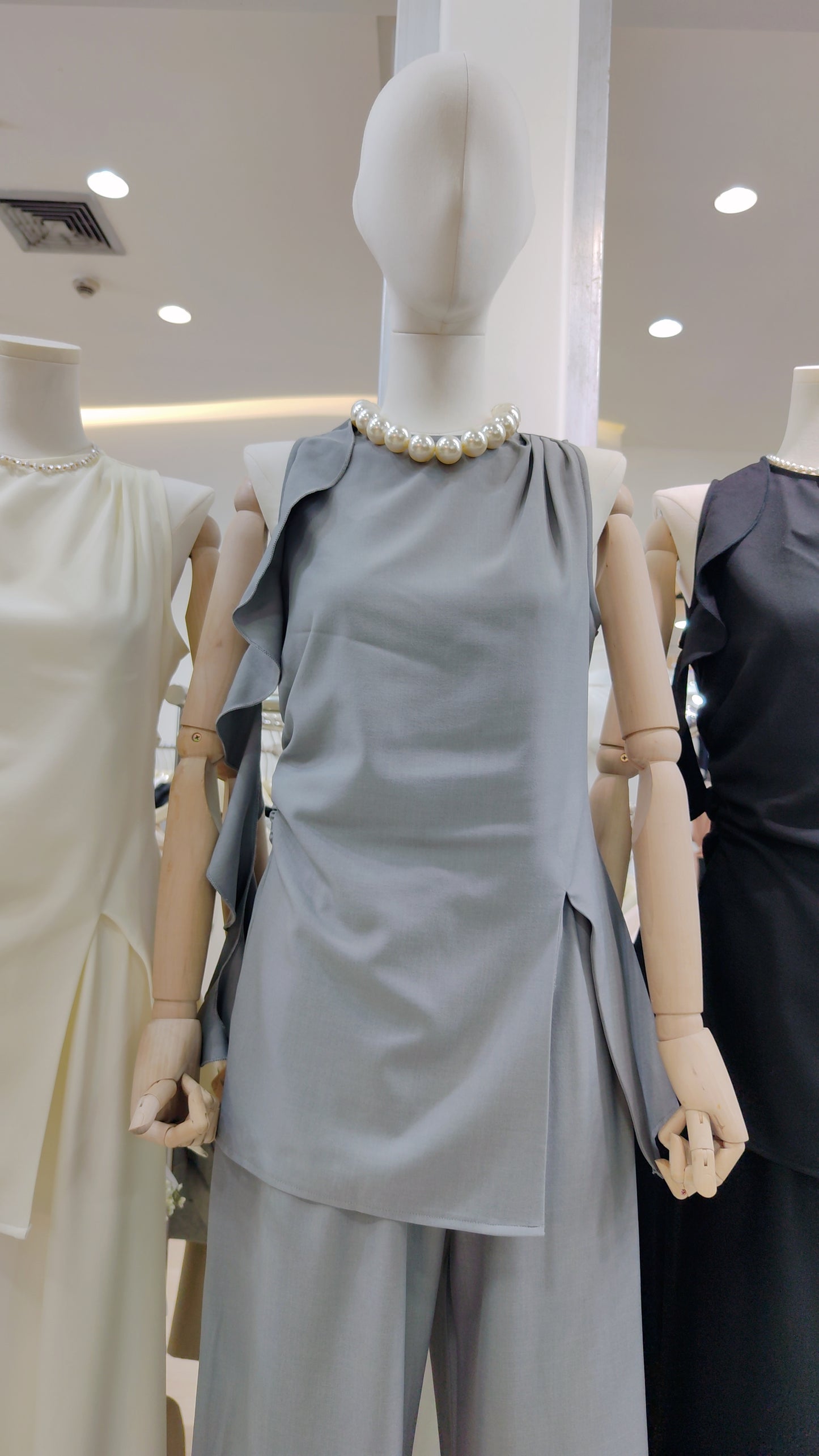The "Flowy Tunic" Two-Piece Set in gray sleeveless top with ruffle hem and matching wide-leg trousers on a mannequin.