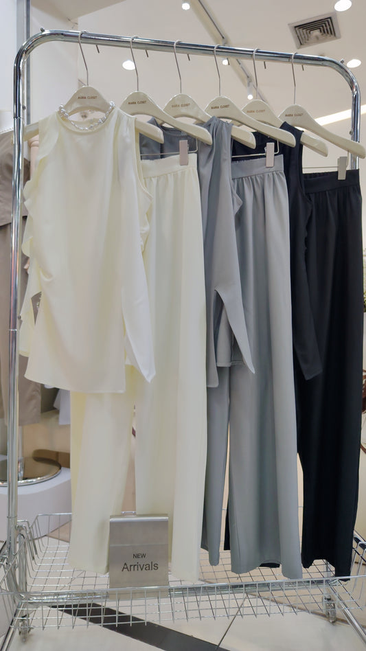 The "Flowy Tunic" Two-Piece Set in cream, gray, and black with sleeveless ruffle tops and wide-leg trousers.