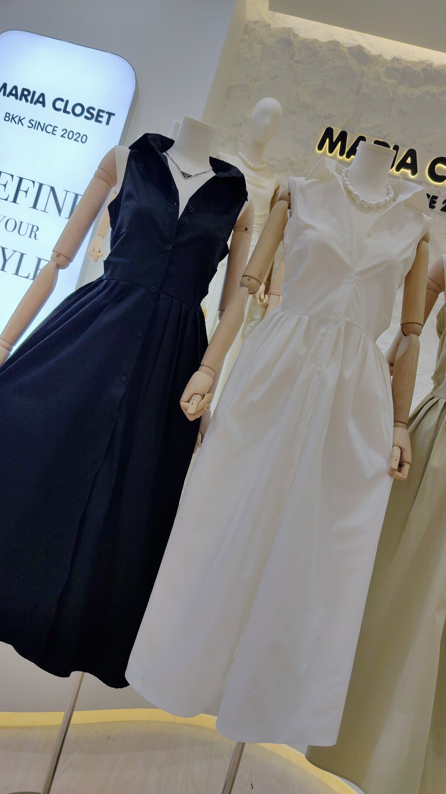 Two mannequins wearing The "Everyday" Sleeveless Shirt Dress in black and white with button-front and classic collar.