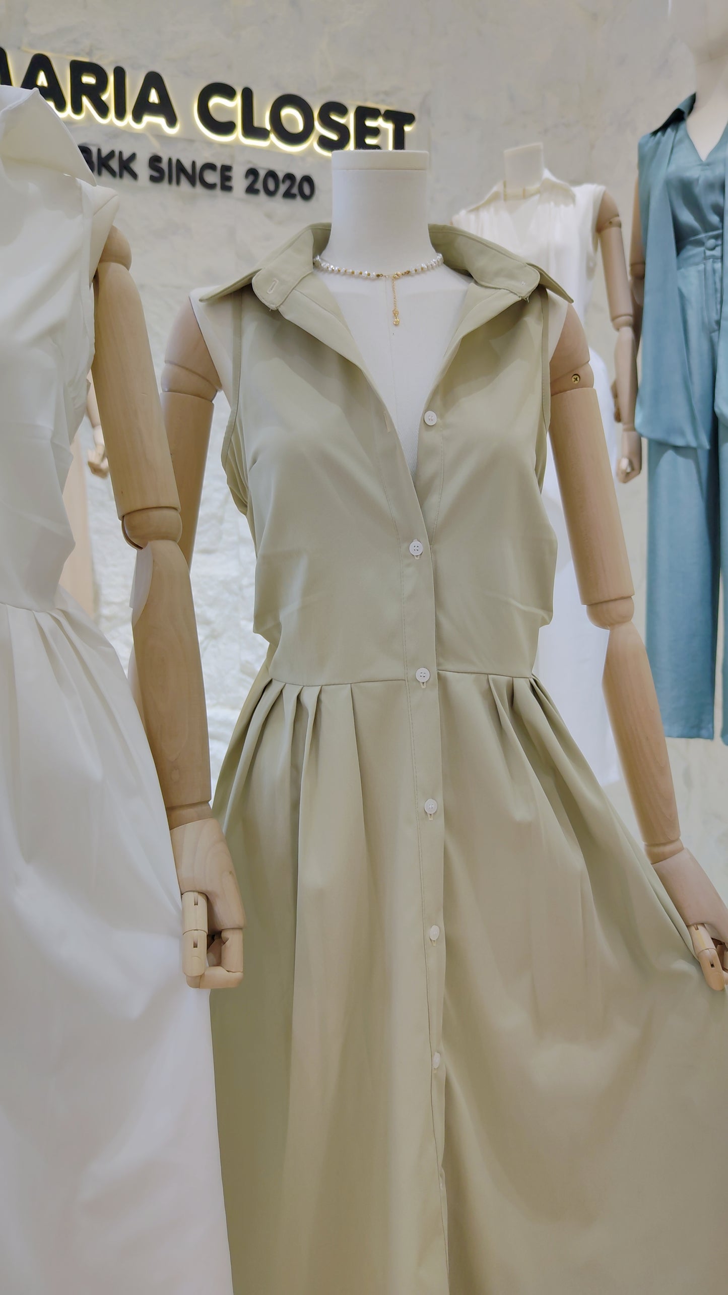 The "Everyday" Sleeveless Shirt Dress in light beige with full button front and classic collar on a mannequin.