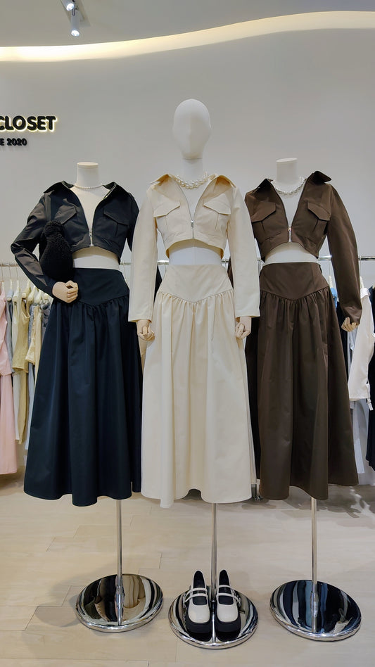 Three mannequins display The Classic Vest Co-ord Set in black, beige, and brown with zip-front vests and long skirts.