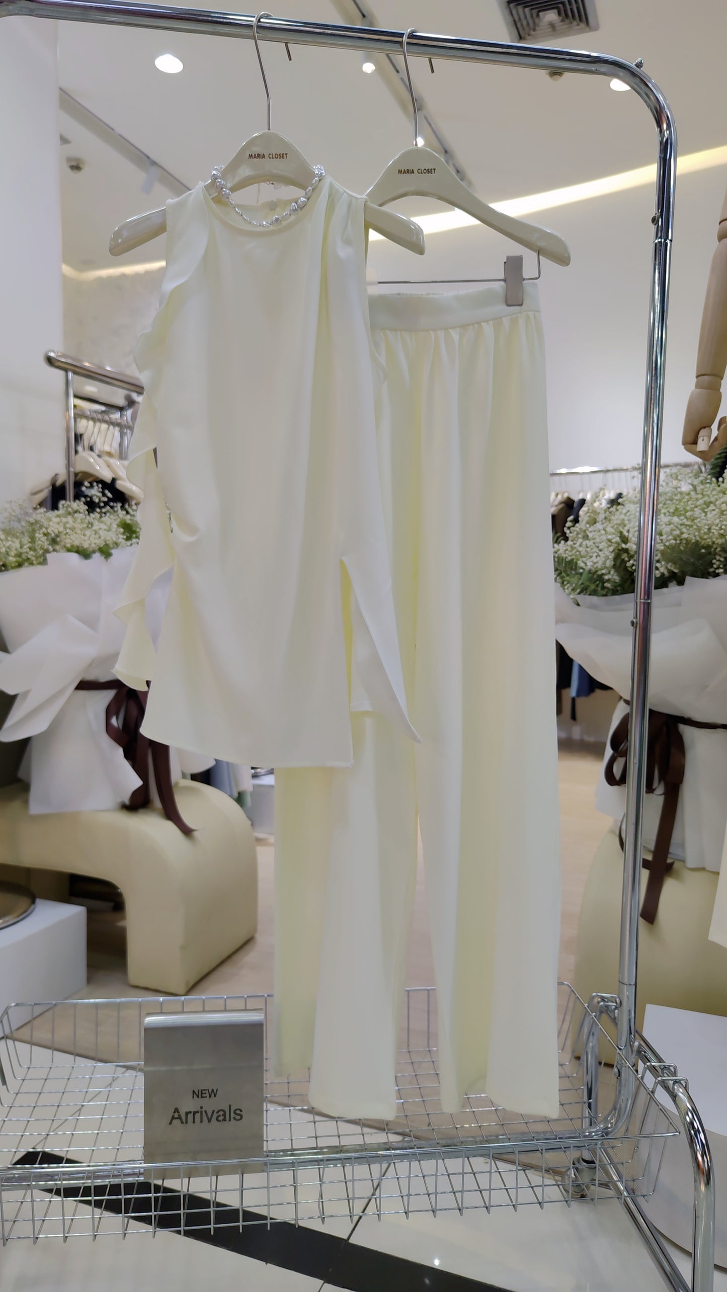 The "Flowy Tunic" Two-Piece Set in white with sleeveless ruffle tunic and wide-leg pants on display.