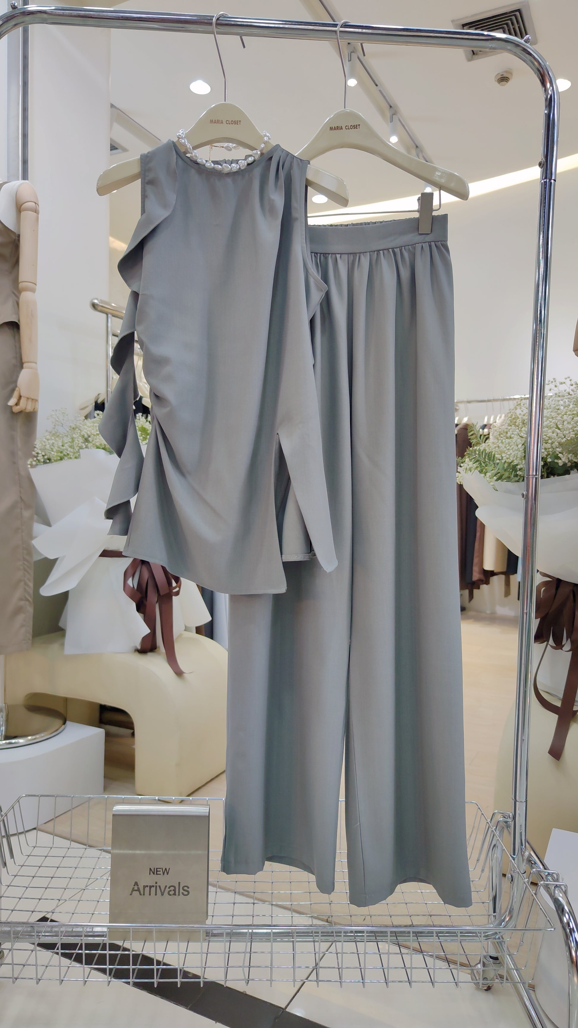 The "Flowy Tunic" Two-Piece Set in soft gray with sleeveless ruffle hem top and wide-leg trousers on hanger.