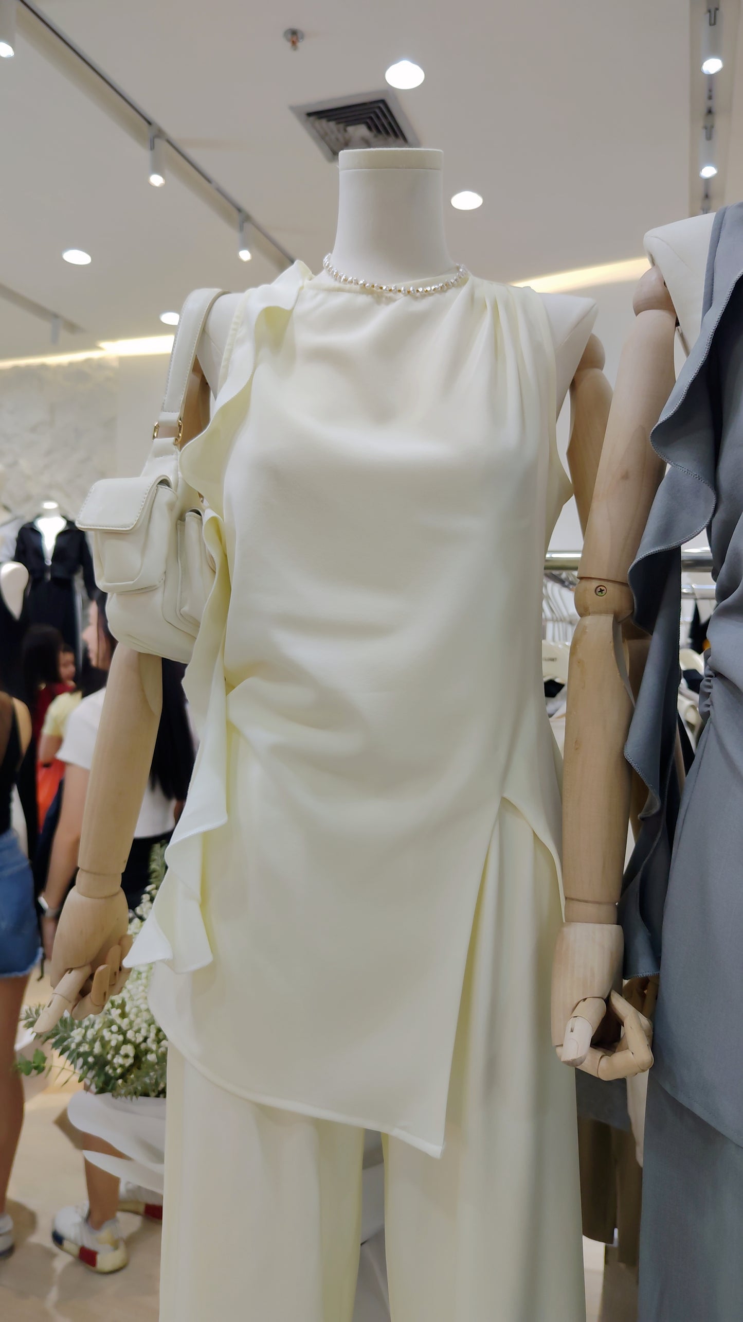 The "Flowy Tunic" Two-Piece Set in cream with ruffle hem sleeveless top and wide-leg trousers on mannequin.