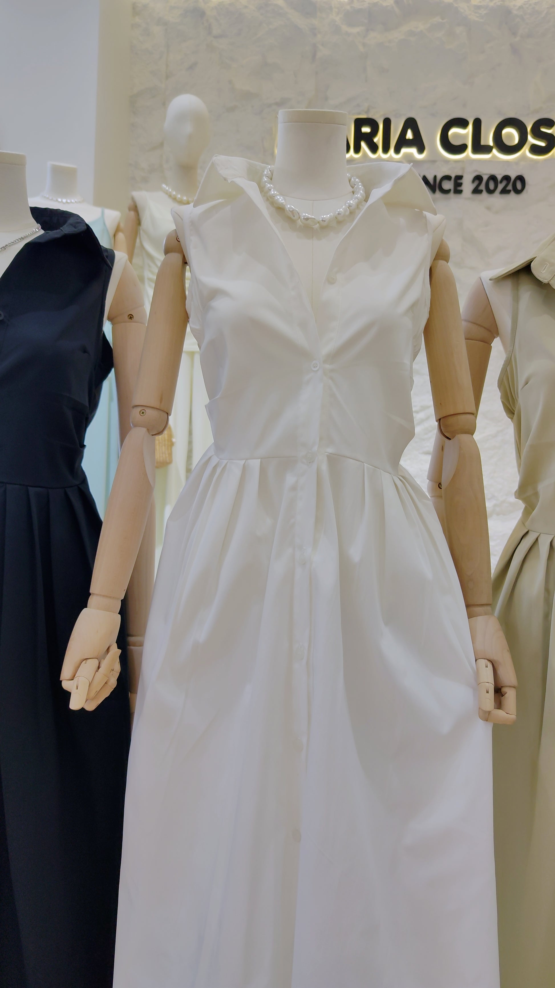 Mannequin dressed in the white "Everyday" Sleeveless Shirt Dress with classic collar and button-front design.